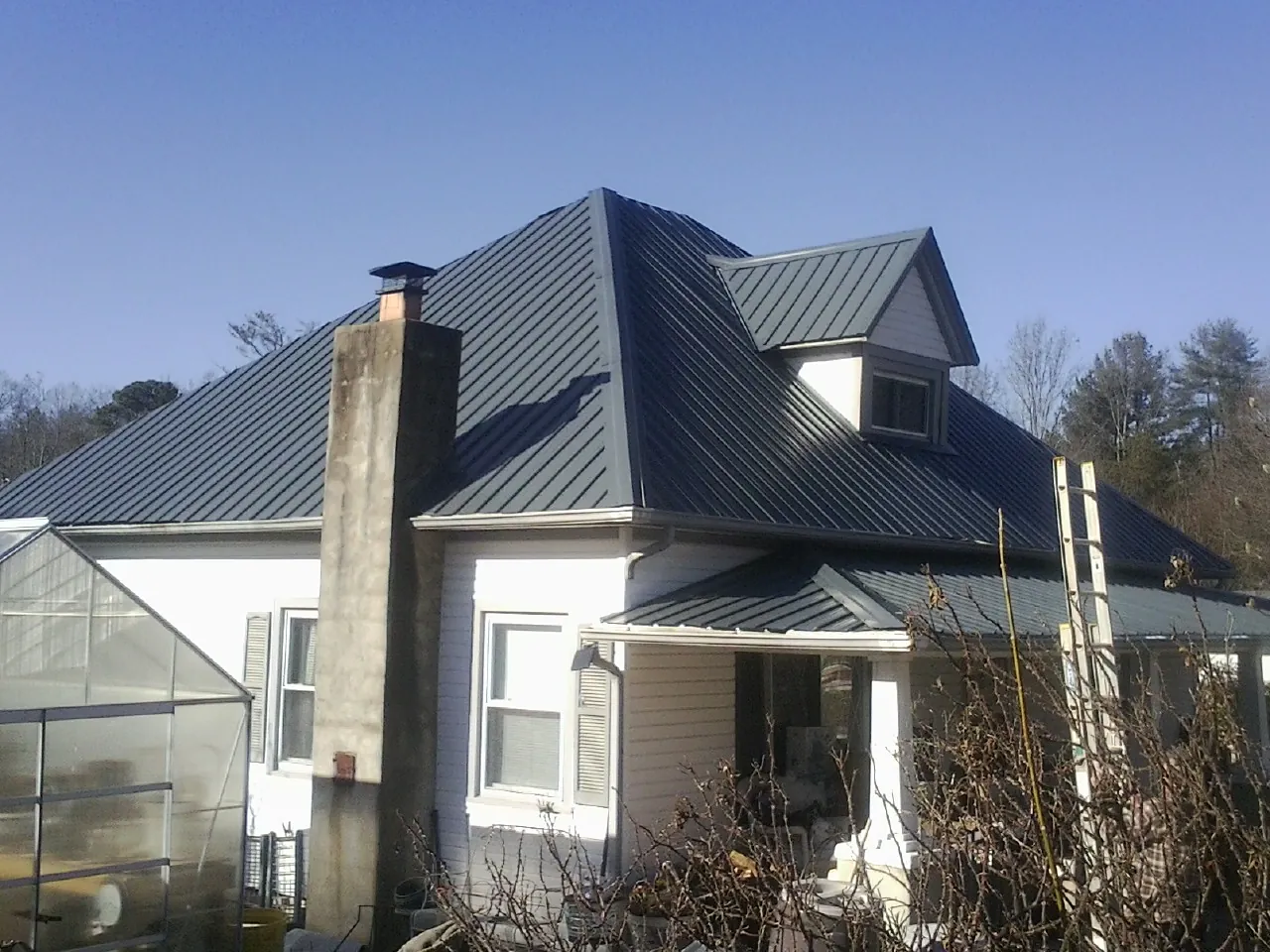 Dark blue standing seam metal roof on a white farmhouse with dormer — Slate & Tile Roof Repair by Roofing Brothers in Le Sueur