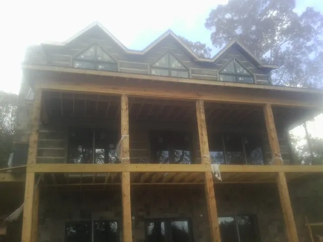 Dormers and porch framing on a large log home under construction — Roof Coating work by our crew in Le Sueur