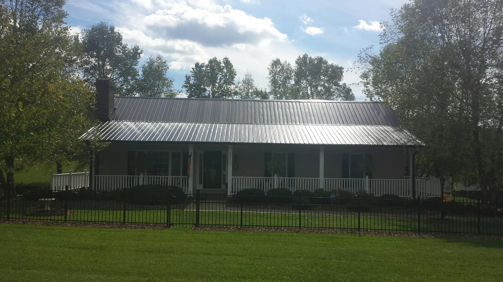 Gray metal roof on a brick ranch with a full width front porch — Gutter Guard Installation work by our crew in Le Sueur