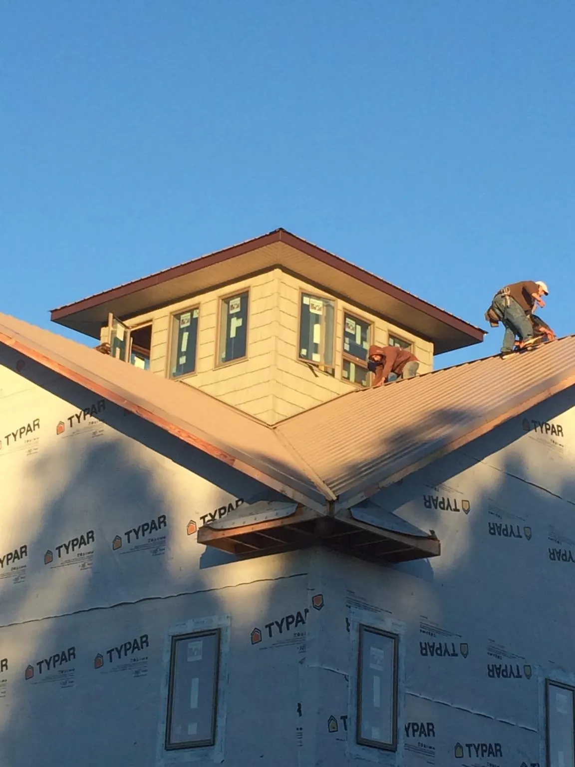 Roofers working around a rooftop cupola on a new metal roof at sunset — Roof Waterproofing in Le Sueur by Roofing Brothers